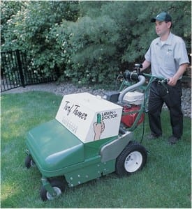Lawn care professional pushing seeding and fertilizing equipment